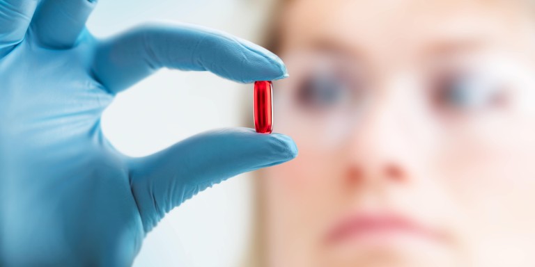 zwischen Fingern gehaltene Kapsel