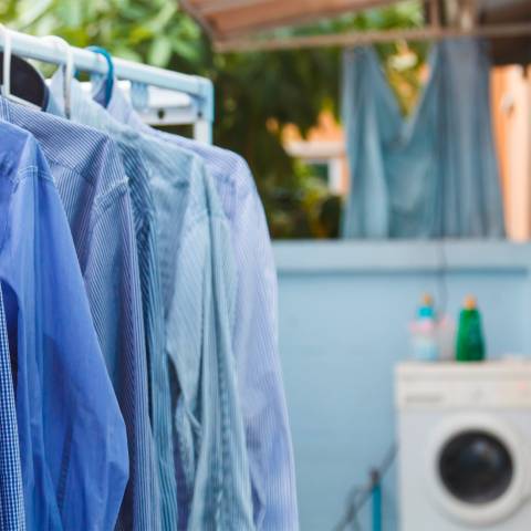 Clothes hanging on a rack with a washing machine in the background