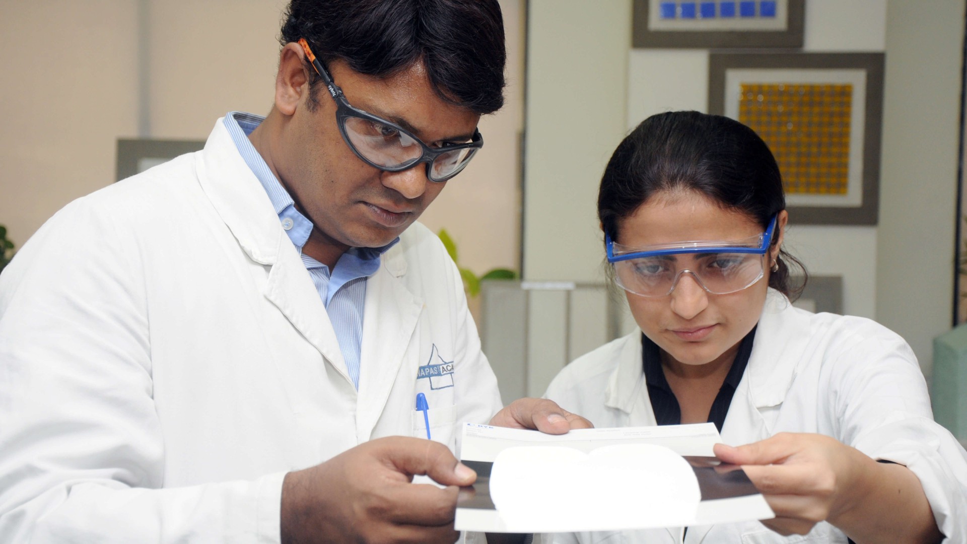 Forscher in wei&szlig;en Kitteln und mit Schutzbrillen