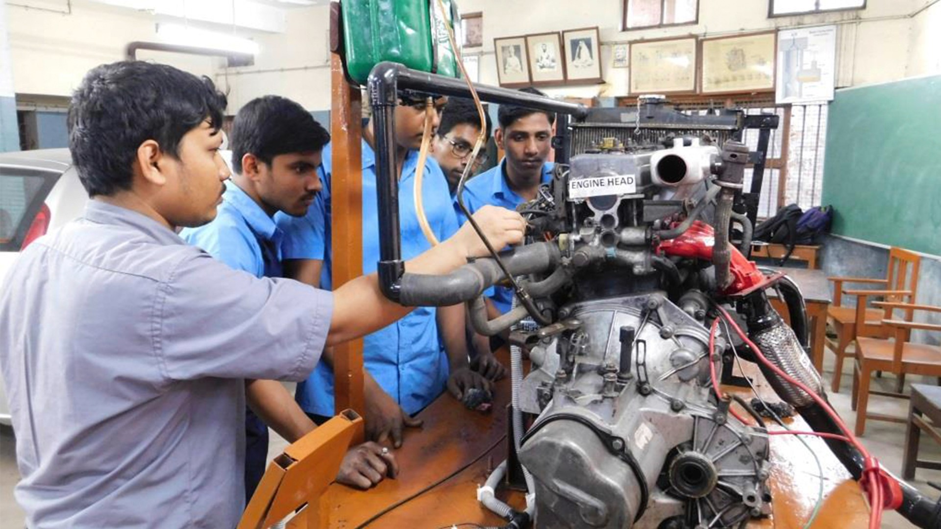Several young men and a teacher work on an engine