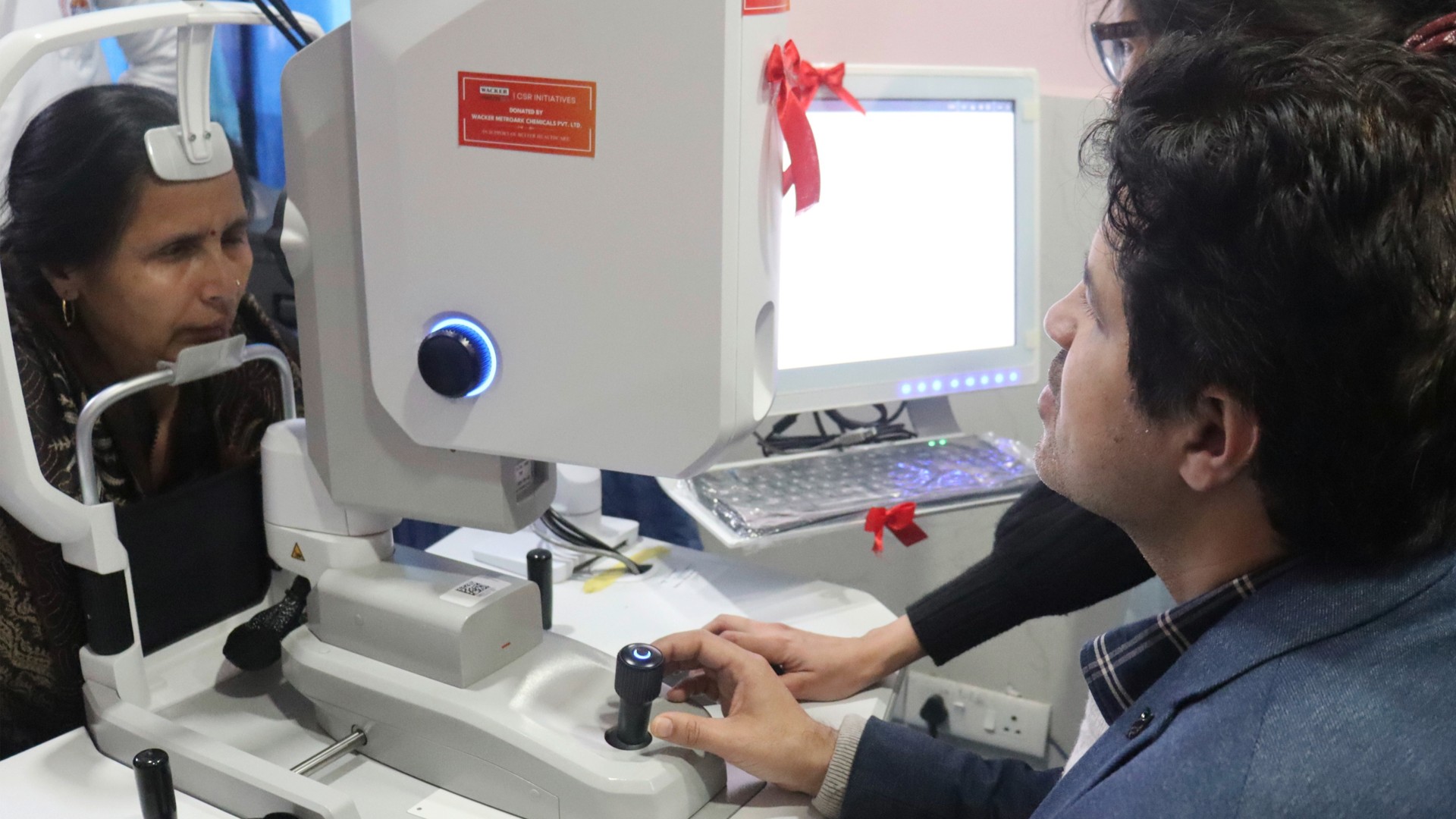 Two specialists carry out an eye test on a woman using an optical device