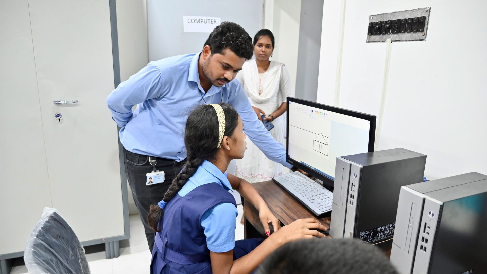 A teacher shows a schoolgirl how to use a computer