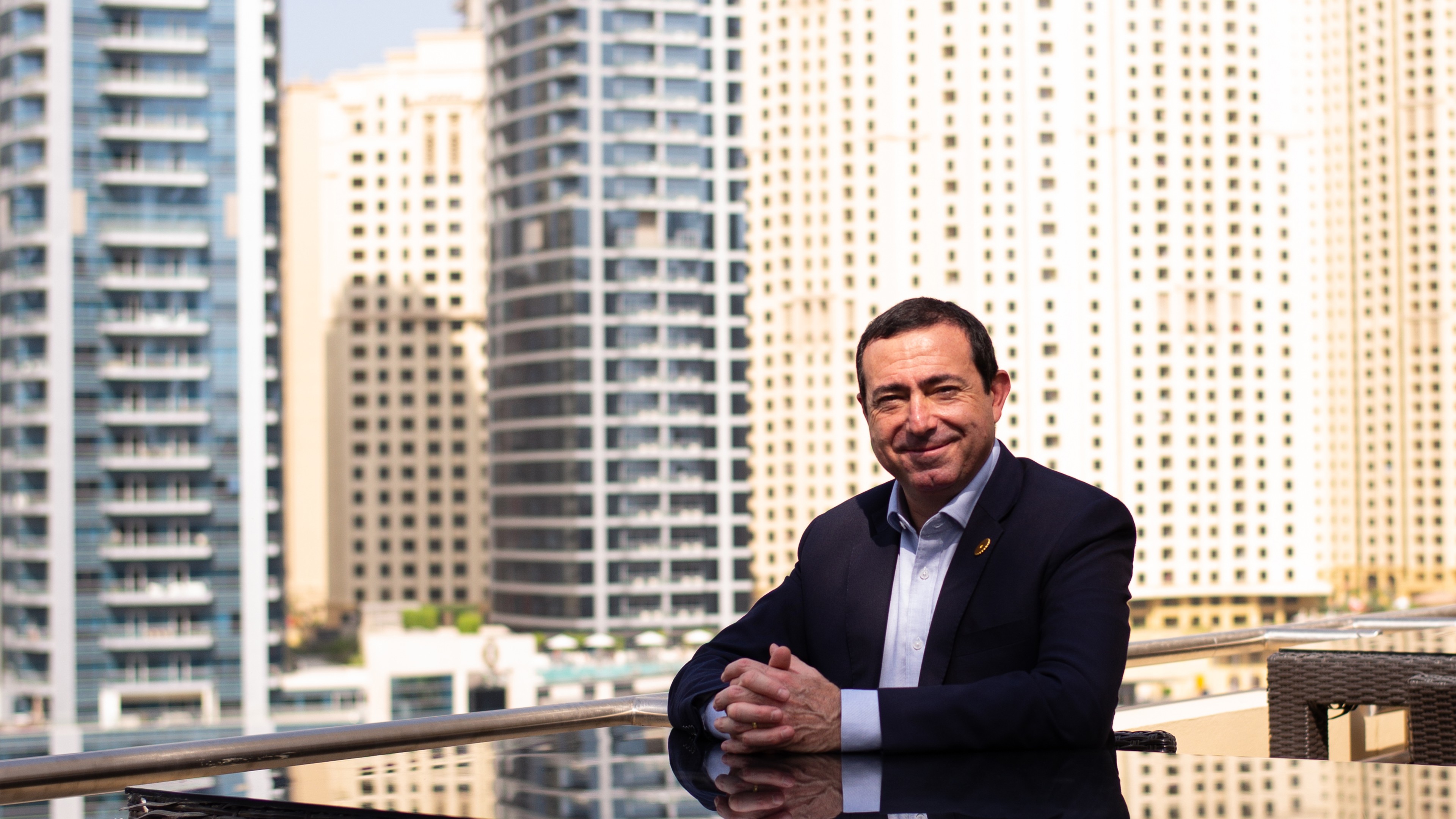 Cyril Cisinski sitzt auf einer Dachterrasse mit Dubai im Hintergrund