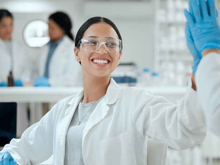 Eine Frau in Laborkleidung beim High Five mit einem Kollegen