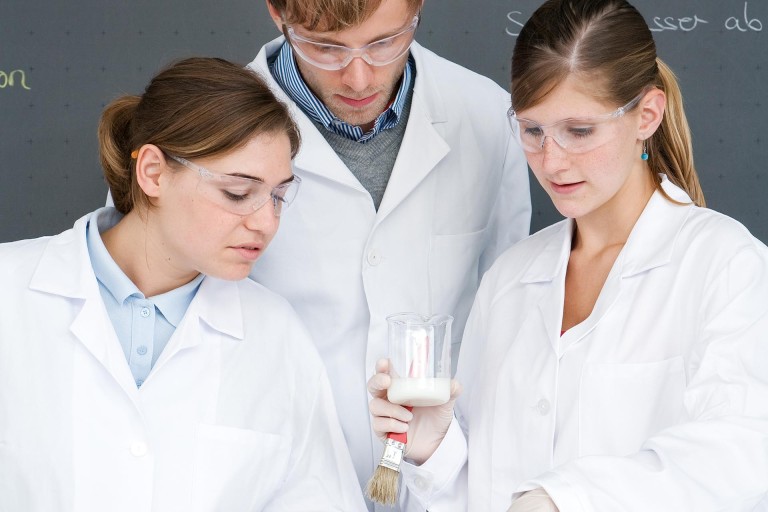 Junge Menschen in Laborkitteln und Schutzbrillen