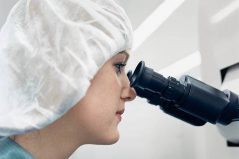 Woman peering into a microscope