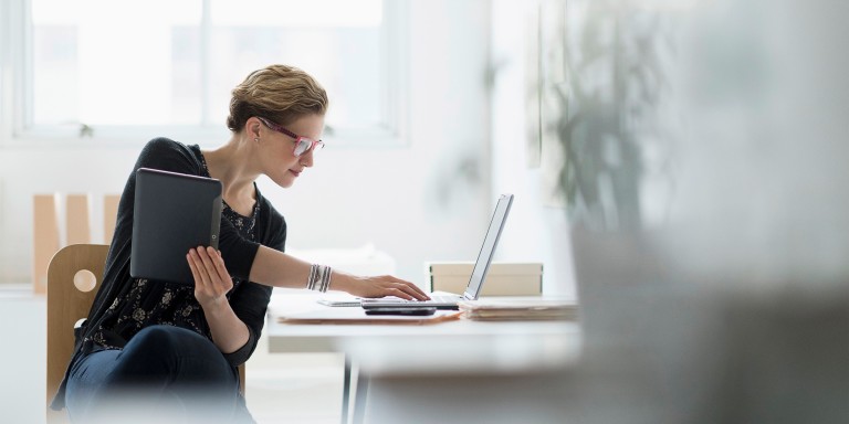 Frau am Schreibtisch mit Laptop und Tablet