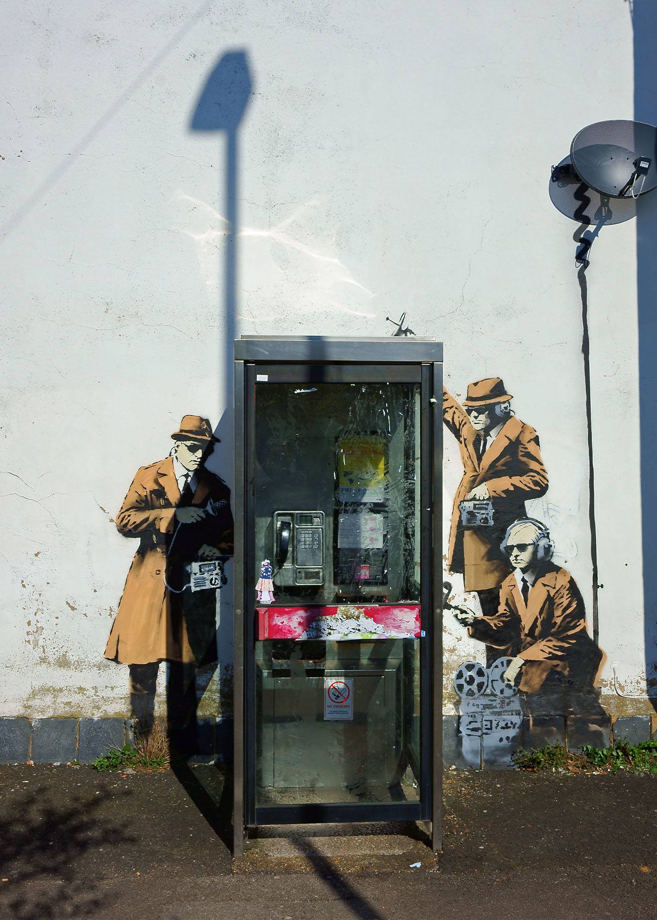 Kunstvoll-ironische Street Art vor einer mittlerweile abgebauten Telefonzelle der Deutschen Telekom. 