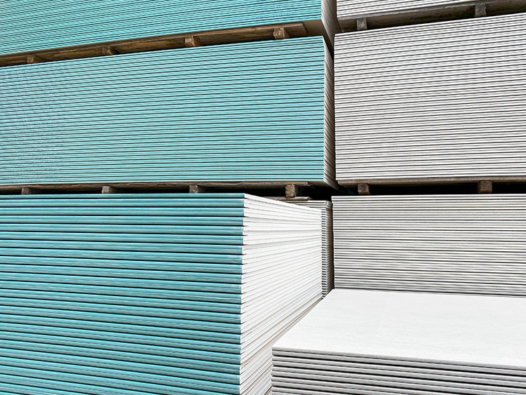 Stacked gypsum boards (hydrophobized: green) on pallets, sorted and ready for use in drywall construction