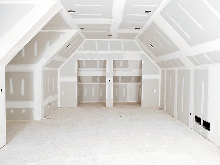 Unfinished interior work in an attic space featuring installed, unplastered drywall panels; joints that have been filled and are visible